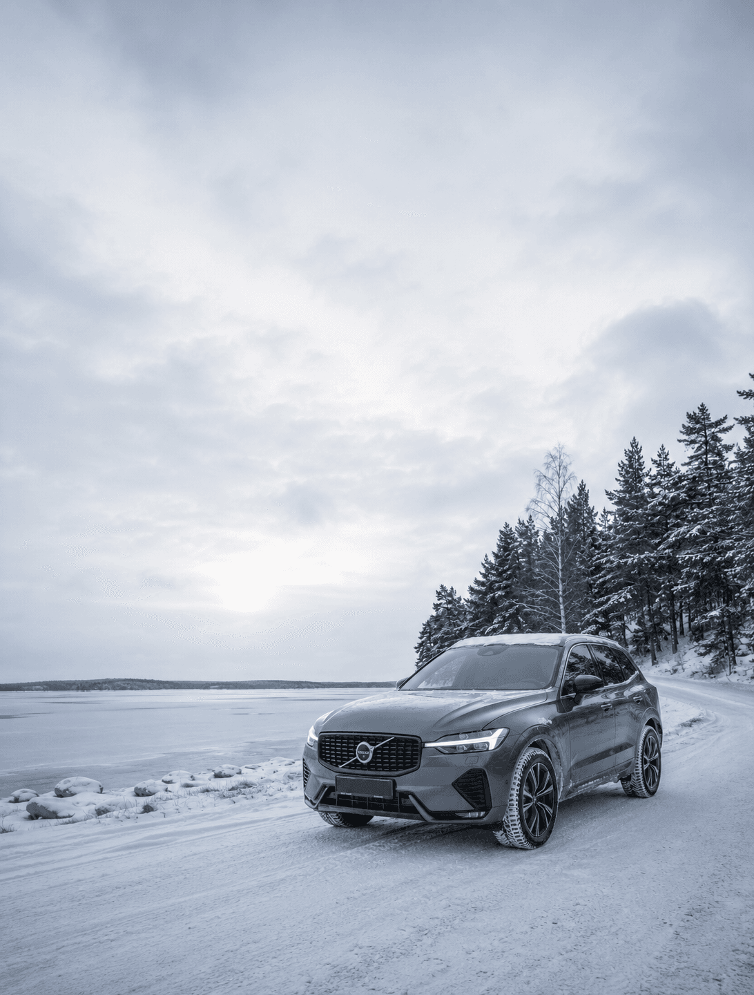 Grafitgrå Volvo XC60 på en snöig väg vid en frusen sjö