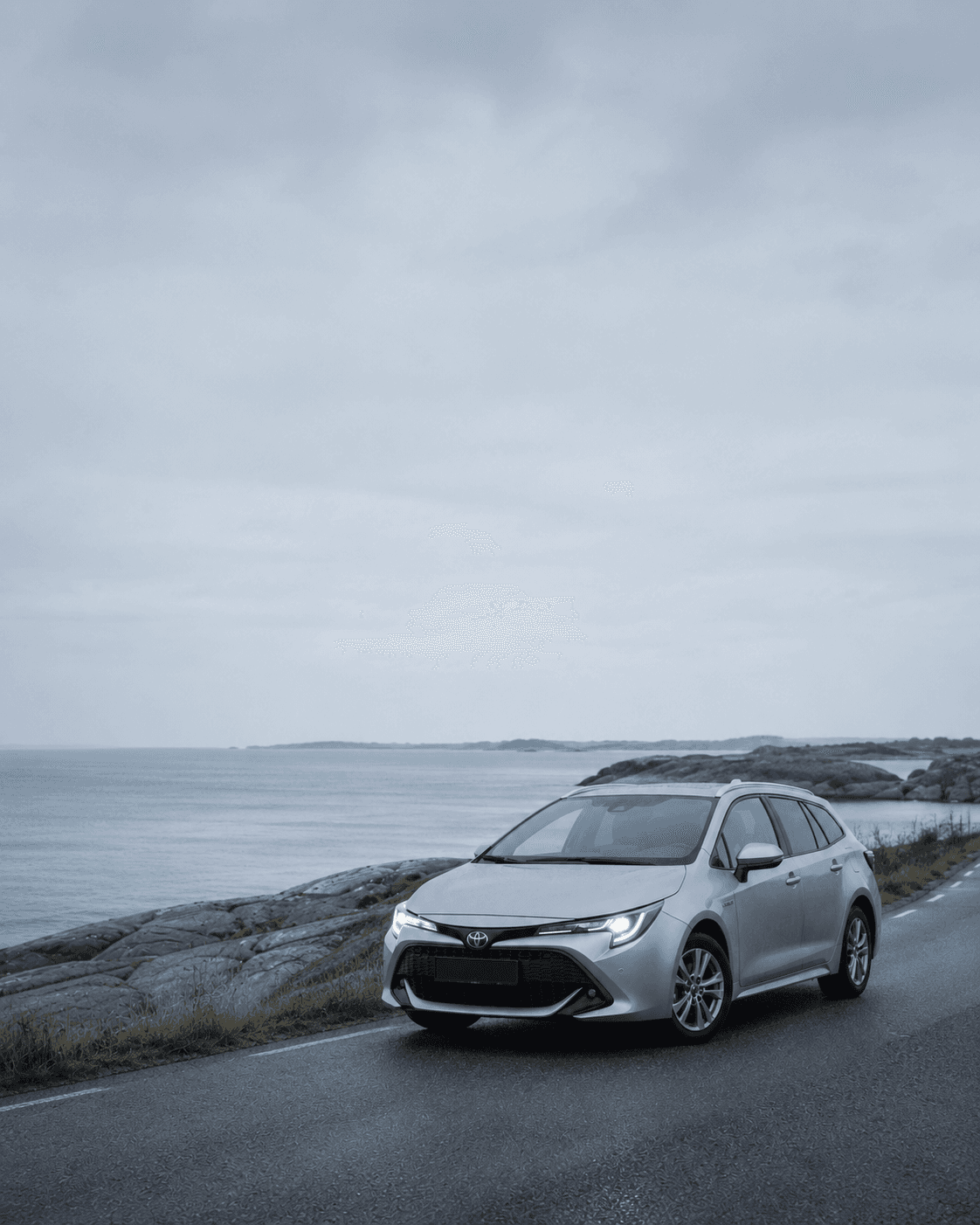 Silverfärgad Toyota Corolla på en kustväg vid Östersjön