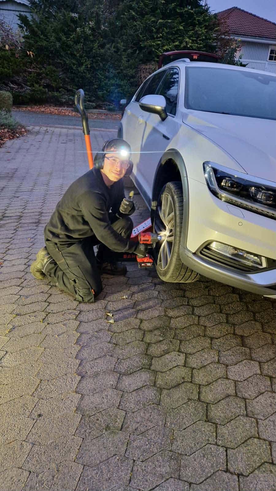 Yaldar Yakhoul ger tummen upp under ett hjulskifte hemma hos en kund i skymningen, med pannlampa tänd